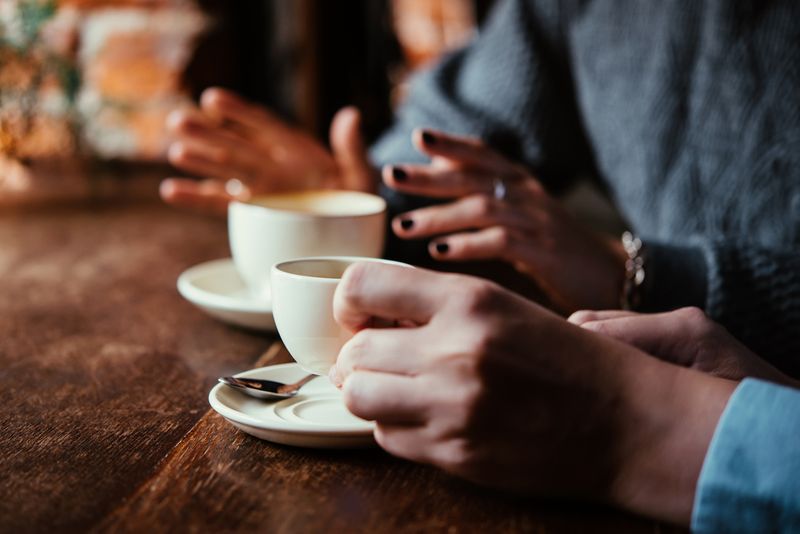 Cafés in Harburg: Kaffeetassen auf Tisch mit Händen