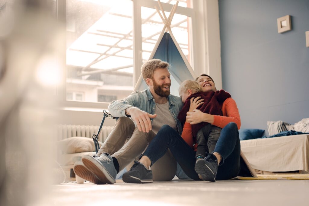 Kindergeld beantragen: Eltern spielen mit ihrem Sohn zu Hause