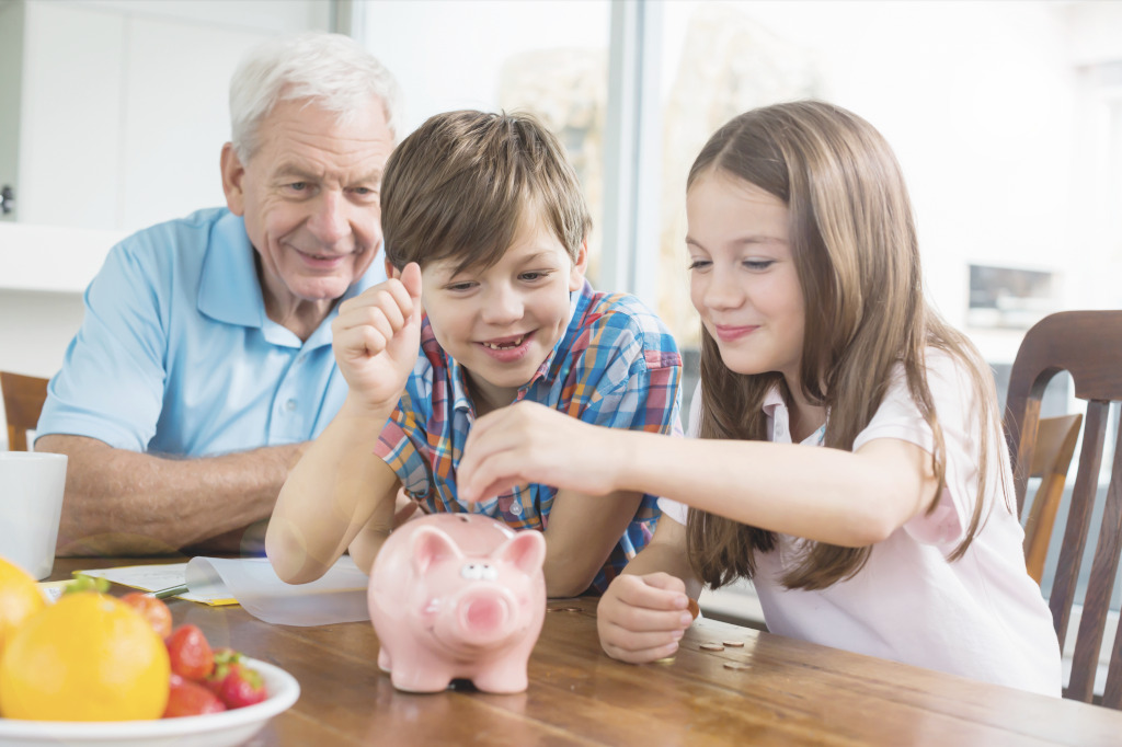 Taschengeld: Ein Opa füttert mit seinen Enkeln ein Sparschwein