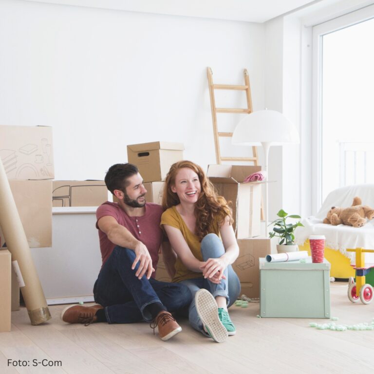 Rund um Immobilien: Pärchen sitzt in neuer Wohnung