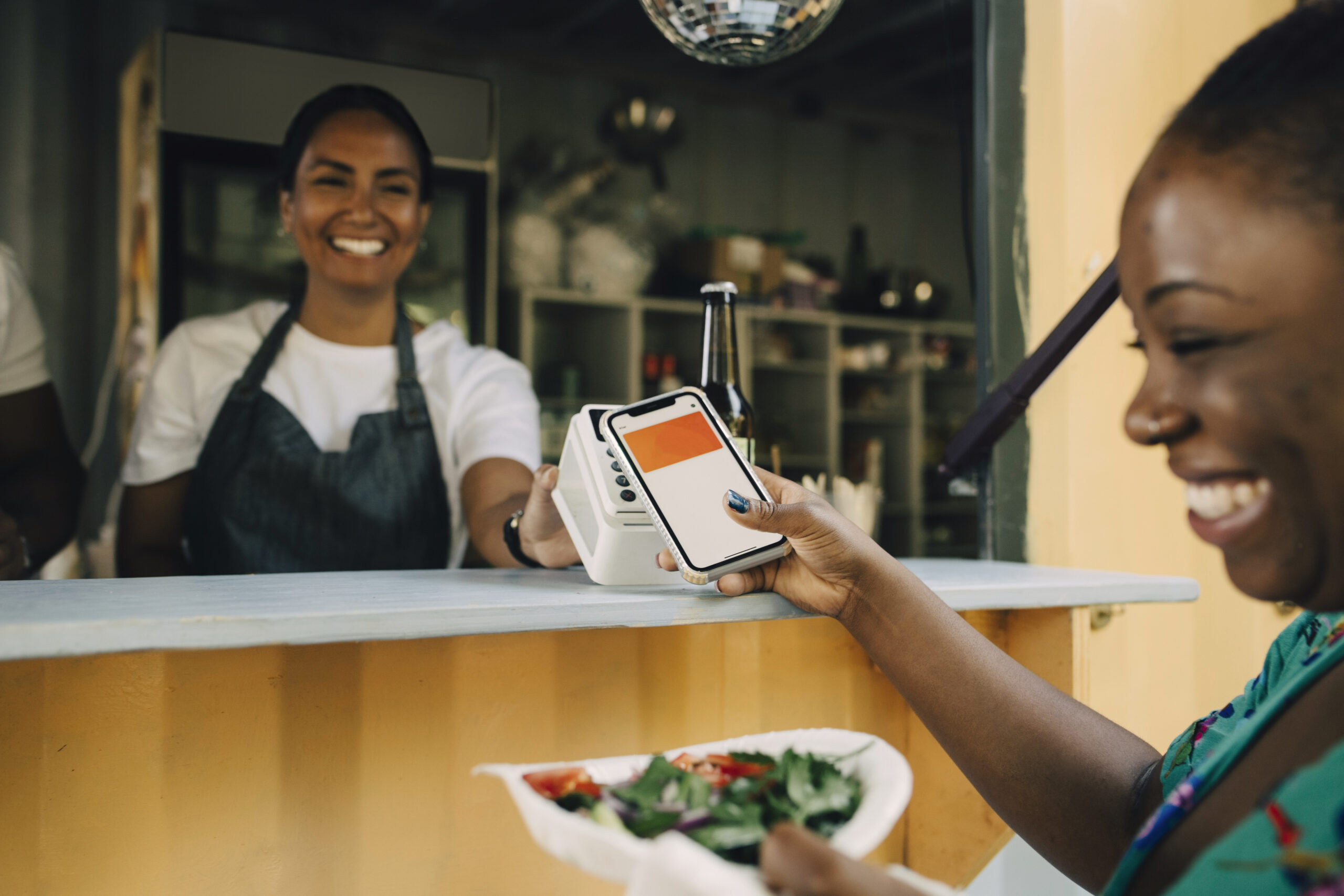 Mobiles Bezahlen in Hamburg: eine Frau bezahlt ihren Snack an einem Imbiss mit dem Smartphone