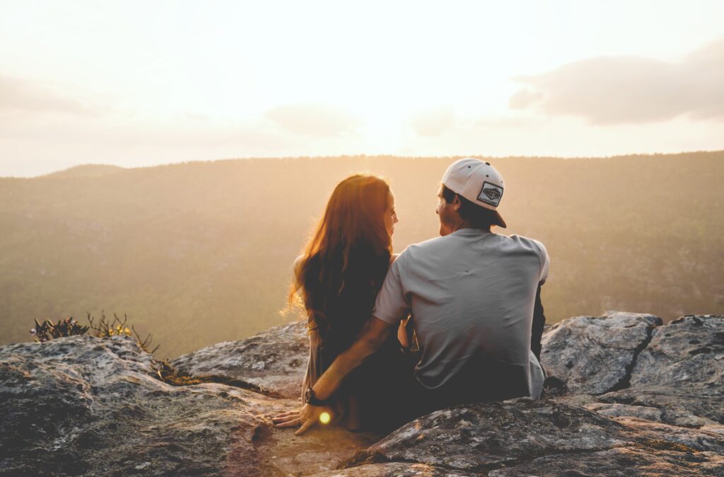 Geld und Beziehungen, junges Paar sitzt auf einem Berg