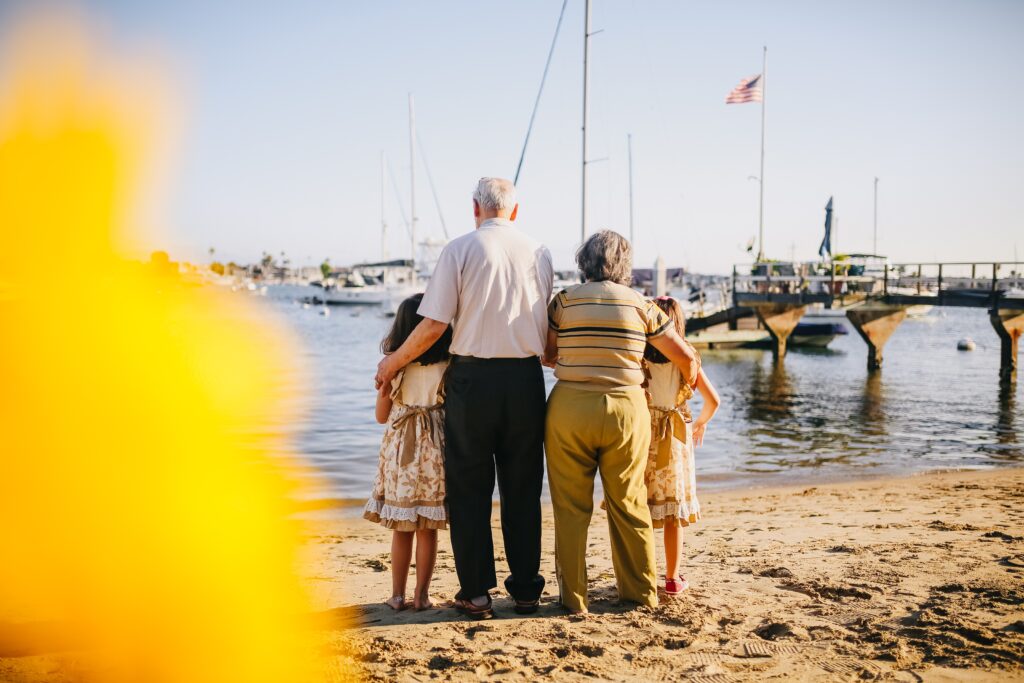 Vorsorgevollmacht mal anders von Jung bis Alt. Großeltern stehen mit ihren Enkelkindern am Wasser. 