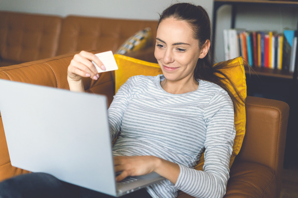 Debit- oder Kreditkarte, Frau vor einem Laptop mit Karte