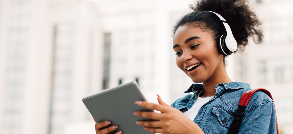 Ausbildung: Junge Frau mit Kopfhörern hält Tablet in der Hand