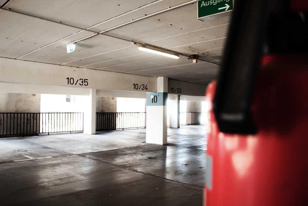 Parken in Hamburg: Leere Parkebene mit Feuerlöscher und "Ausgang"-Schild im Vordergrund