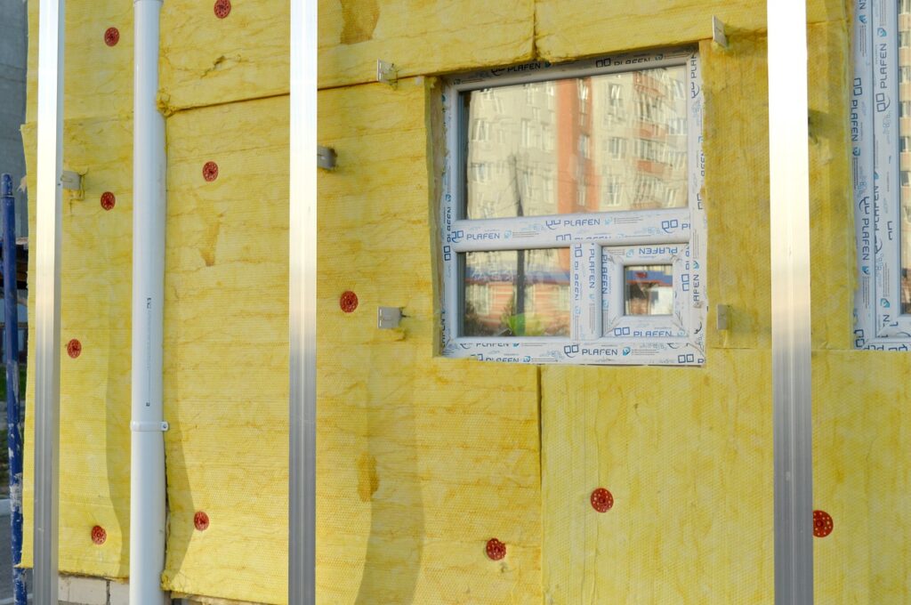 Fassadendämmung Kosten, Wärmedämmung der Fassade: gelbes Dämmmaterial an Hauswand