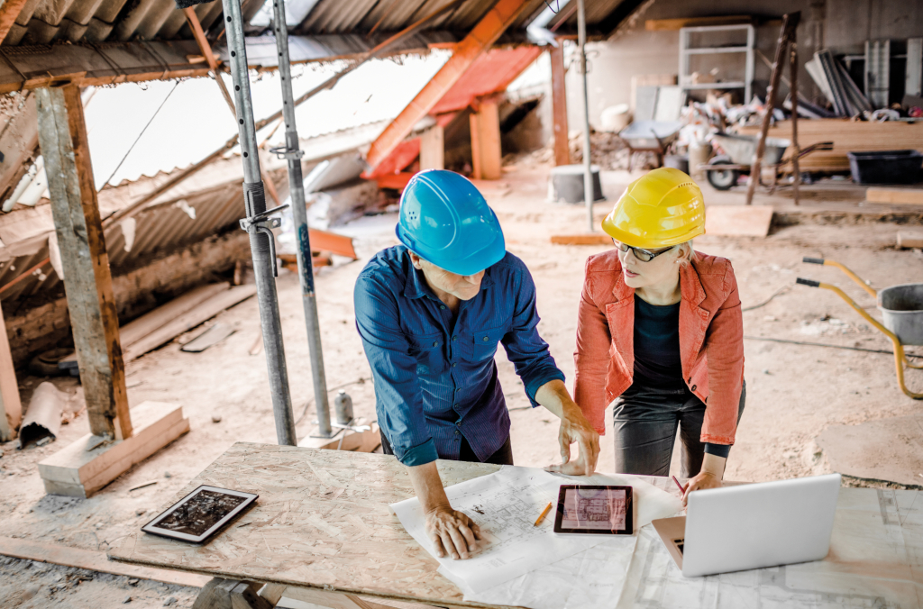 Energetische Sanierung Förderung: Architekt:innen über Baupläne in renovierungsbedürftigen Dachgeschoss