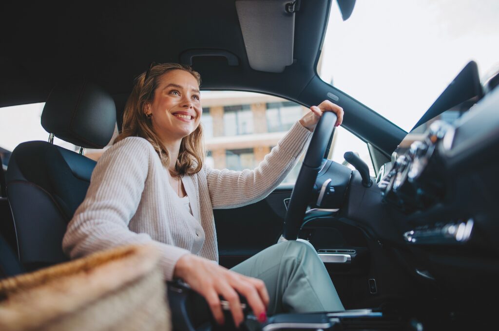 gebrauchtwagen kaufen: Eine junger Frau sitzt am Steuer eines Autos