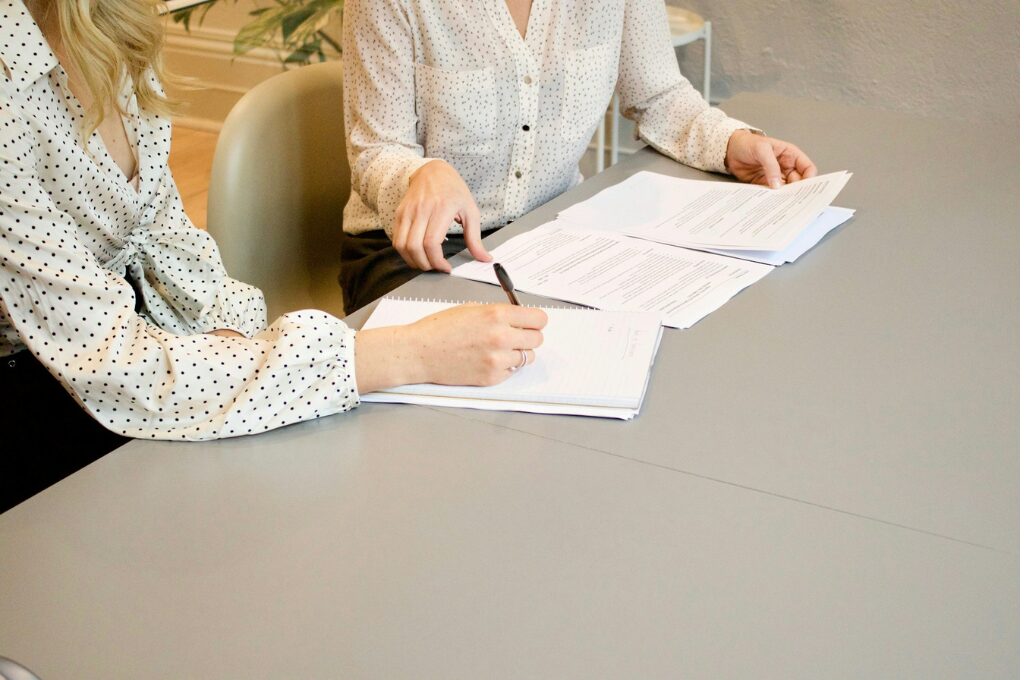 Berufsunfähigkeitsversicherung: 2 Frauen sitzen an einem Tisch und blicken auf einen Vertrag