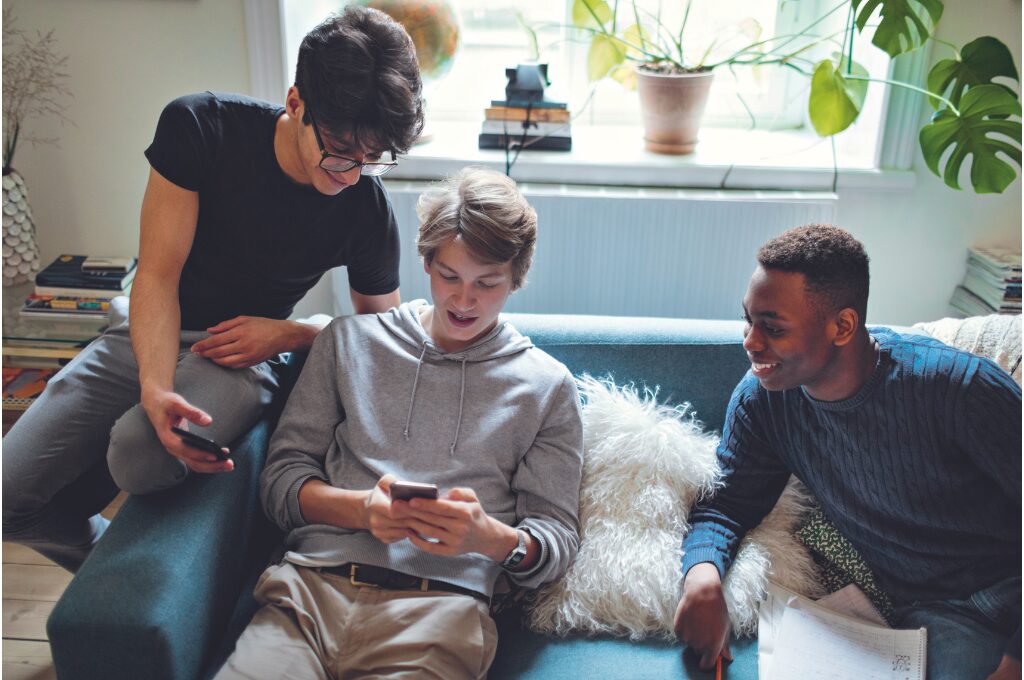 In-Game-Käufe: Drei Jugendliche schauen auf ein Smartphone