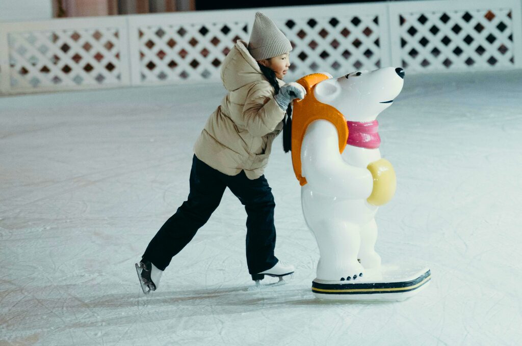 Schlittschuhlaufen in Hamburg, Kind mit einer Stütze auf der Eisbahn