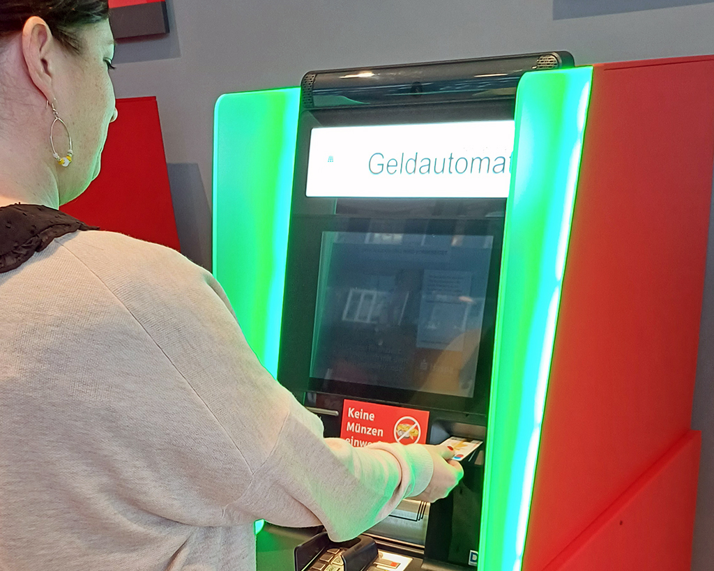 Shouldersurfing: Eine Frau hebt Geld an einem Automaten ab