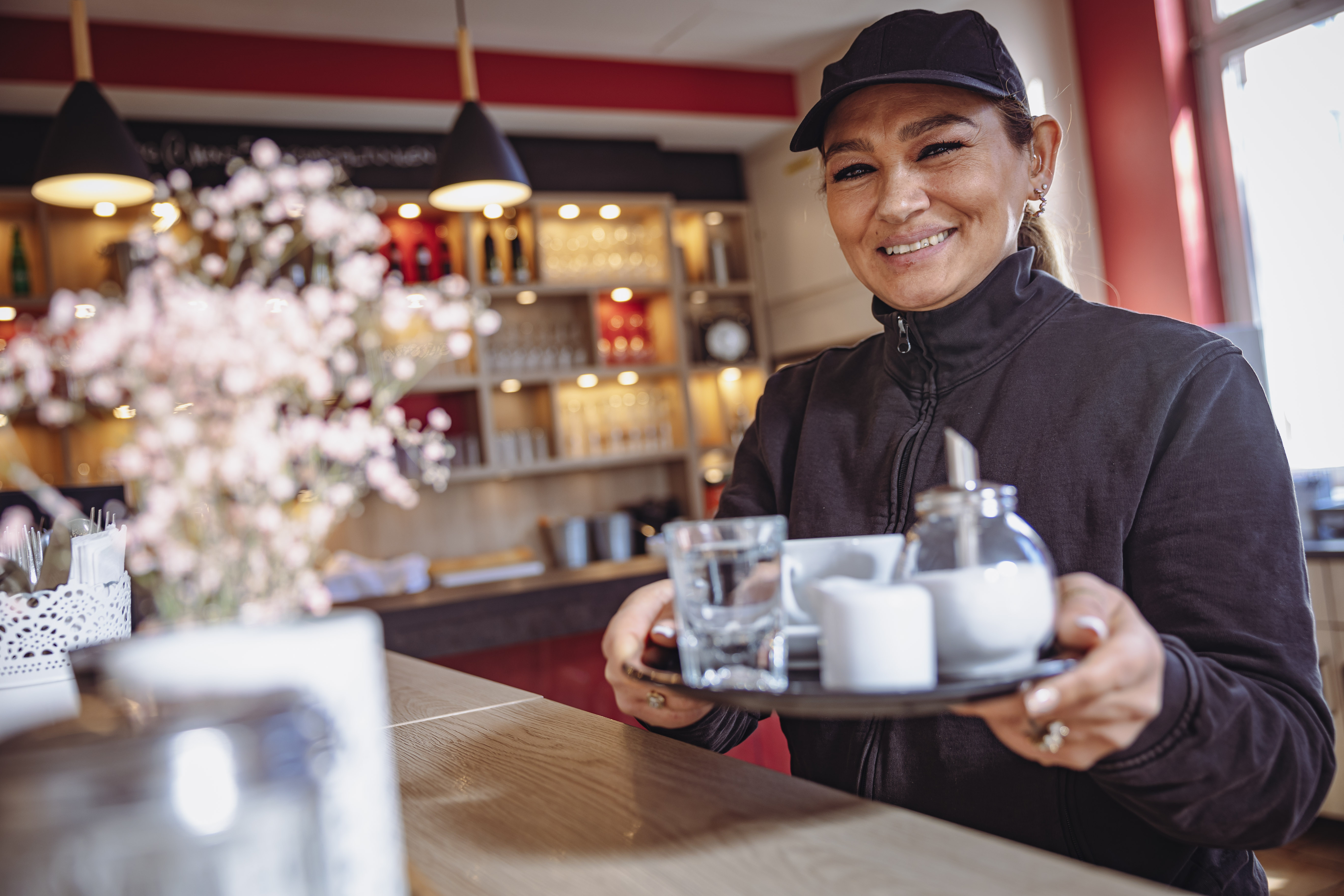 Haus 5: Eine Frau trägt ein Tablett mit Kaffee und Zucker