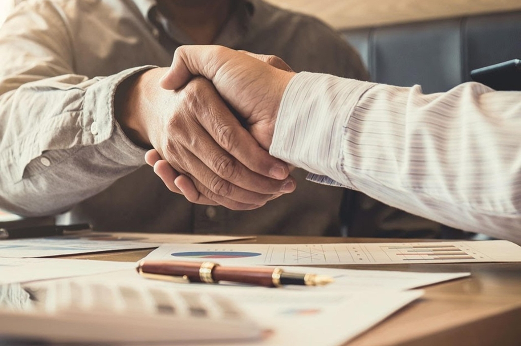Zwei Männer schütteln sich die Hand über Statistiken