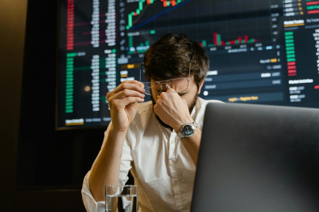 Anlagebetrug durch Cybertrading: Ein Mann sitzt verzweifelt vor seinem Laptop