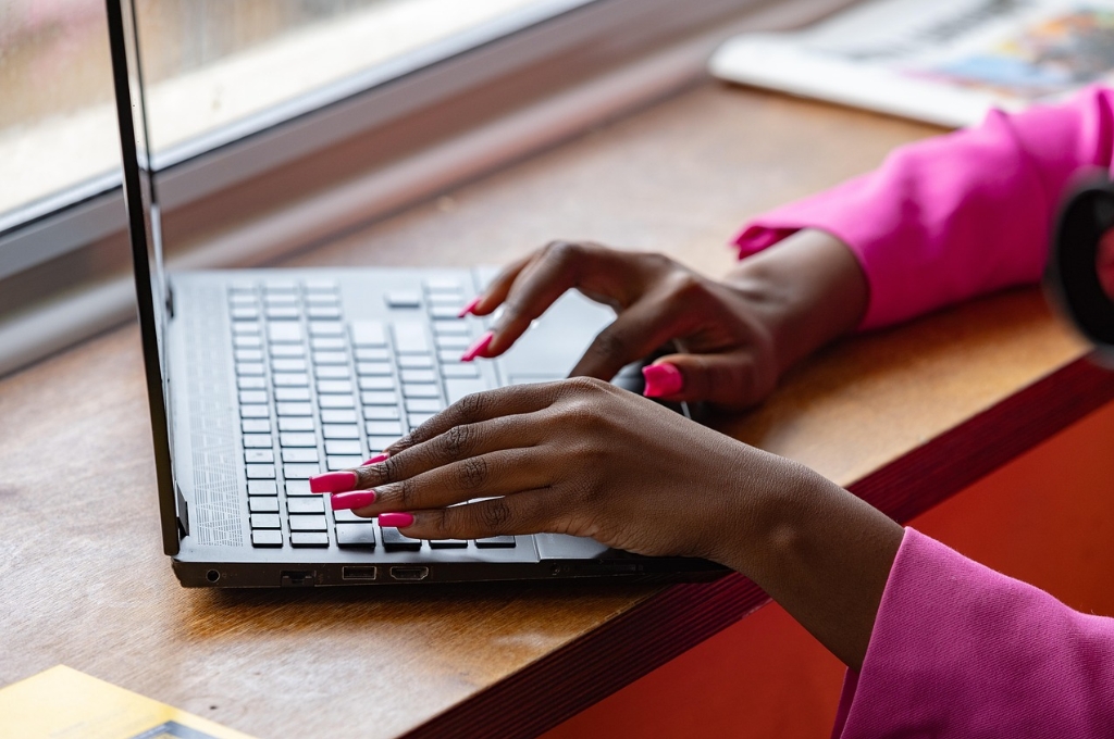Manikürte dunkle Frauenhände tippen auf Laptop