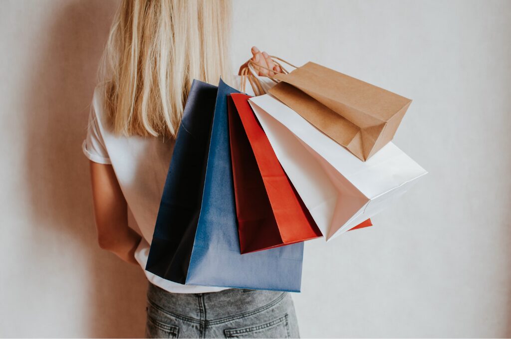 Buy Now Pay Later, Frau hält bunte Einkaufstüten in die Kamera