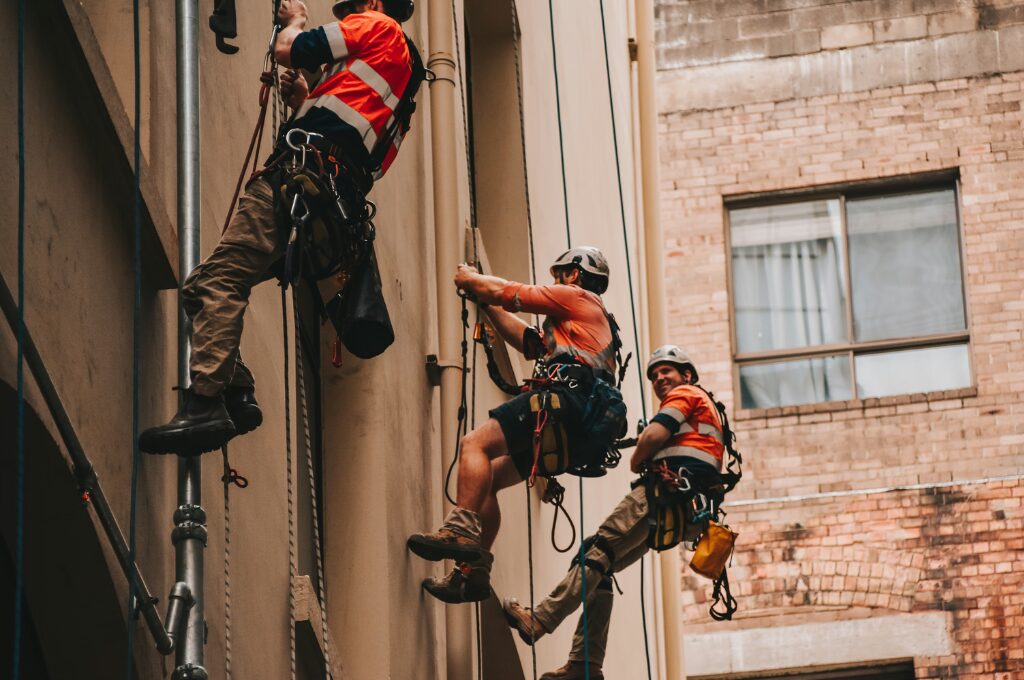 Arbeitsrechtliche Begriffe, Männer die in Arbeitskleidung eine Wand entlang klettern