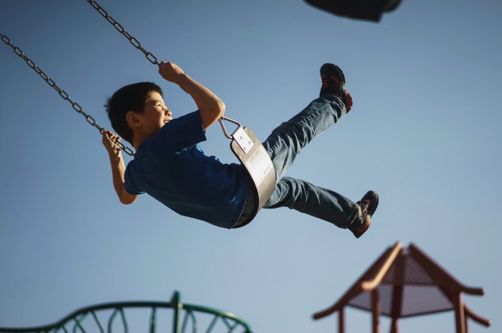 Bildung und Teilhabe, kleiner Junge auf einer Schaukel