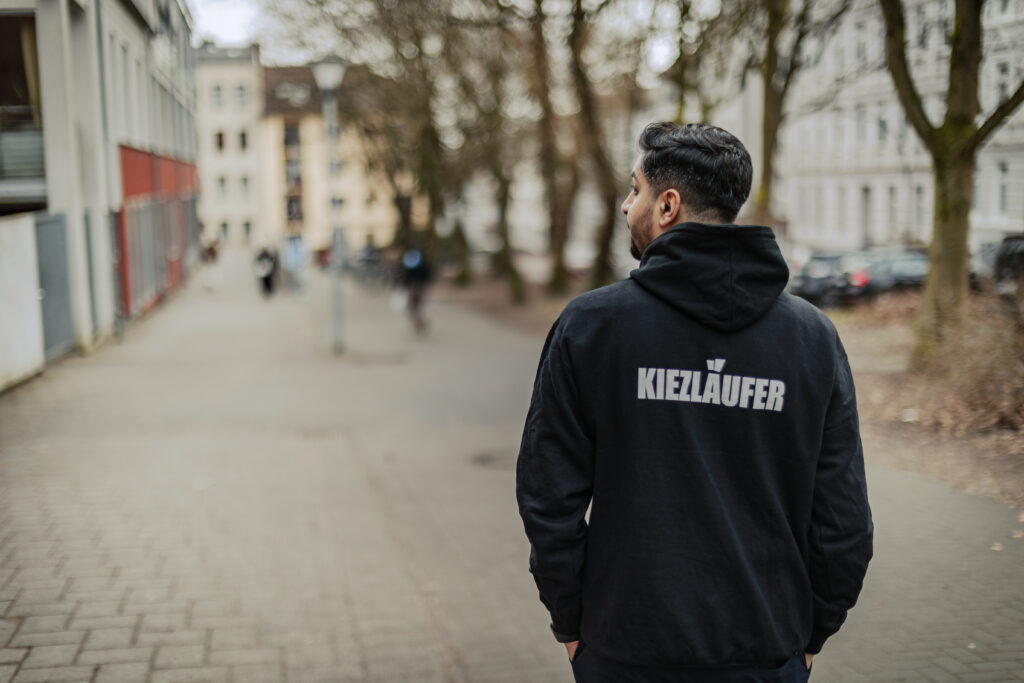 Kiezläufer: Ein junger Mann steht mit dem Rücken zur Kamera.