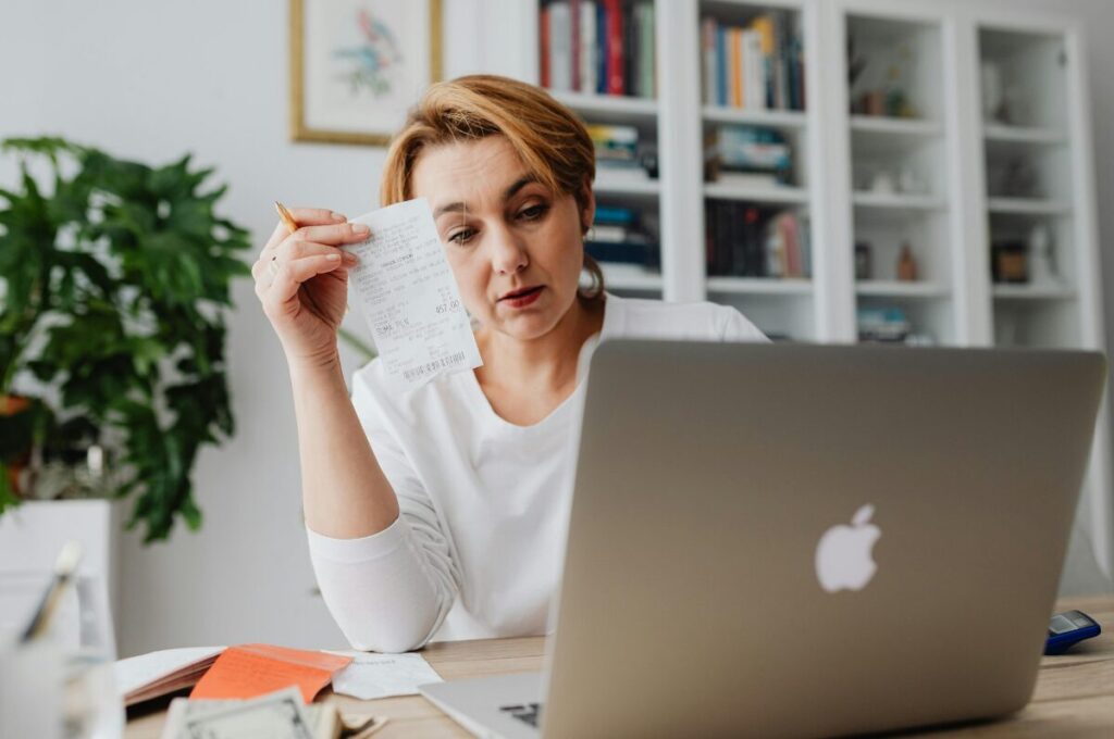 Bürgergeld, Frau vor ihrem Laptop mit Einkaufsbon
