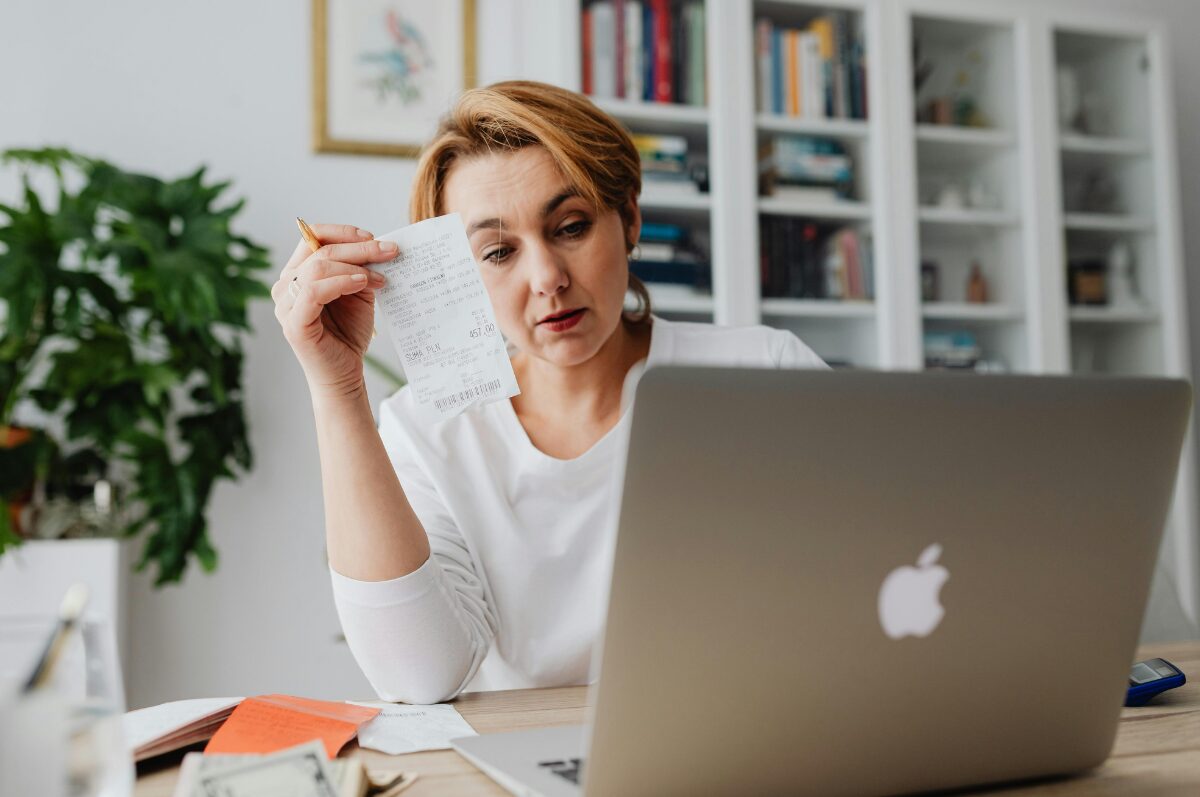 Bürgergeld, Frau vor ihrem Laptop mit Einkaufsbon