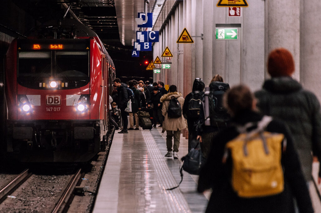 Stranded Traveller Scam, Bahnhofsgleis mit Bahn und Passagieren