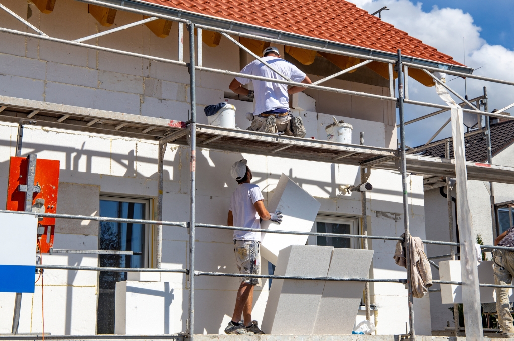 Bauarbeiter isolieren eine Hausfassade