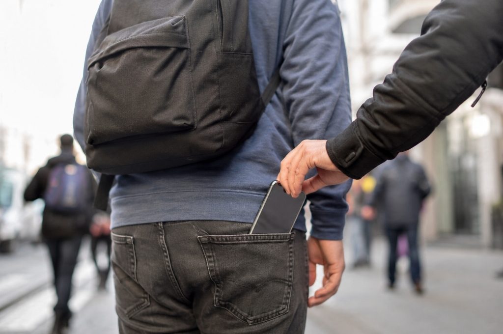 Taschendiebstahl: Ein Mann zieht einem anderen Mann ein Handy aus der Tasche