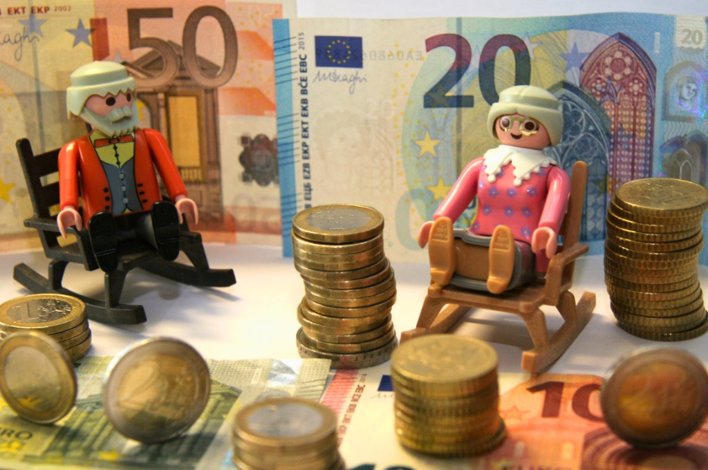 Spielfiguren Oma und Opa umgeben von Münzen und Geldscheinen