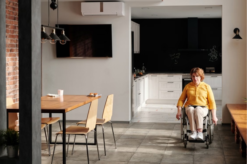 Eine Frau im Rollstuhl sitzt in einer modernen K&uuml;che und zeigt die Barrierefreiheit im Wohnungsdesign (barrierefrei umbauen)